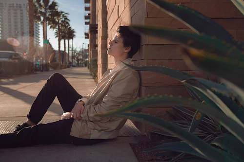 human man leaning on brown wooden wall person