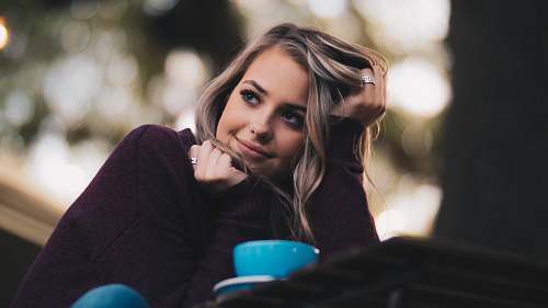human woman in purple long-sleeved top holding her hair person
