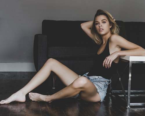human woman sitting near black sofa while holding her head person