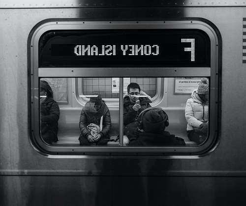 black-and-white grayscale photo of persons sitting on train subway