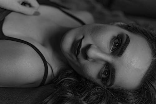 black-and-white grayscale photo of woman lying on bed human