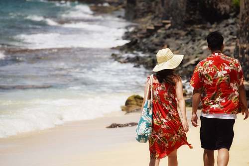 human man and woman walking on seashore during daytime people