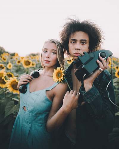human man holding corded device standing beside woman wearing blue dress people