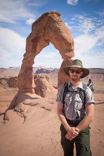 human man standing near Delicate Arch people