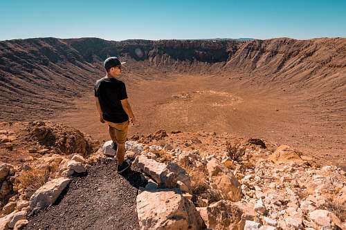 mountain man wearing black shirt standing on rock formation during daytime human