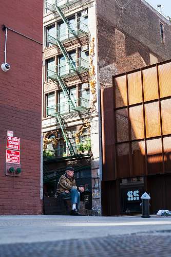 human person sitting on bench beside building people