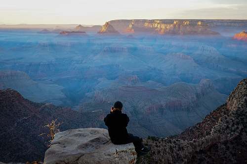 human person sitting on rock cliff people