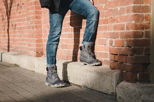 people person standing beside brown brick wall human