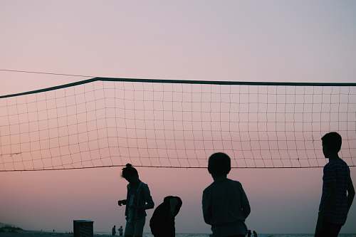 human silhouette of four people playing volleyball during nighttime people