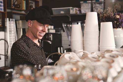 human smiling man beside cups people