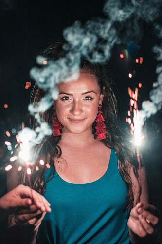 human woman holding lighted sparkler taken during night time people