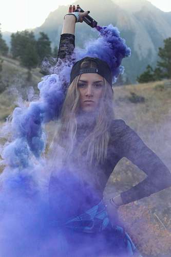 human woman raising purple smoke bomb during daytime people