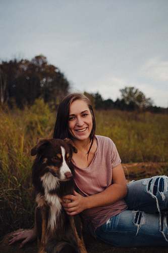 human woman sitting beside a black and white dog dog