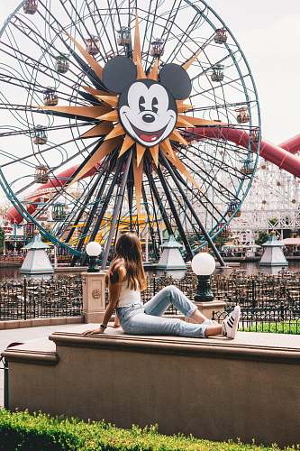 human woman sitting on brown concrete table near ferris wheel amusement park
