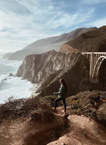 human woman standing on top of mountain looking at sea promontory
