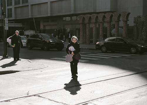 people woman walking along street wearing black coat car