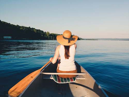 boat woman wearing sunhat riding boat on body of water canoe