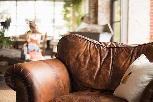 human white throw pillow on brown leather armchair person