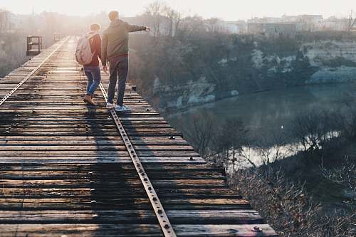 bridge two boy standing on brown train track bridge near river rochester