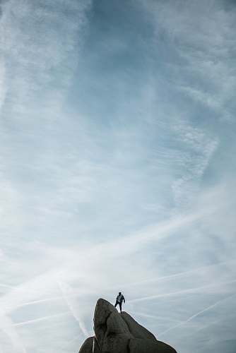 sky man standing on cliff under white sky joshua tree national park