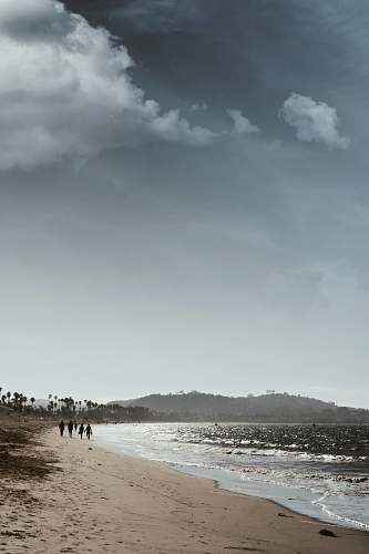 beach people walking near seashore during daytime grey