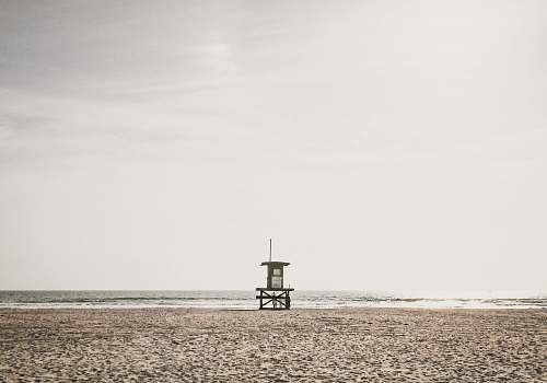grey photo of lifeguard station near shoreline beach