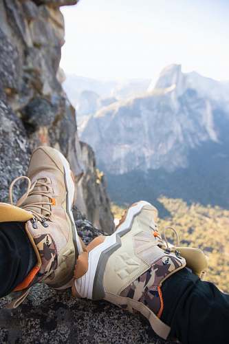 apparel person sitting on rock near gray fault-block mountain clothing
