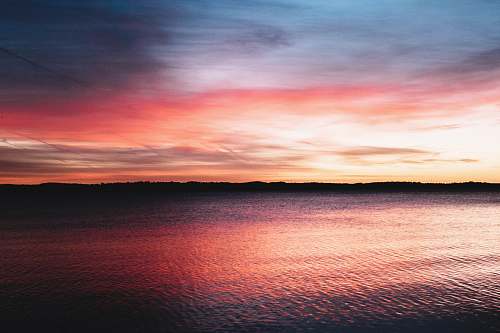 sunset calm body of water during sunset photo sunrise