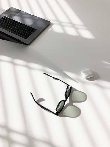 sunglass flat-lay photography of wayfarer-style sunglasses and MacBook Pro glasses