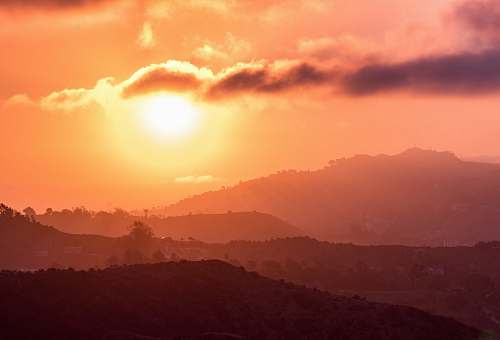 sunset silhouette photo of mountains by the setting of the sun sky