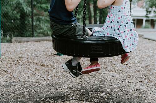 kid two children playing on tire swing toy