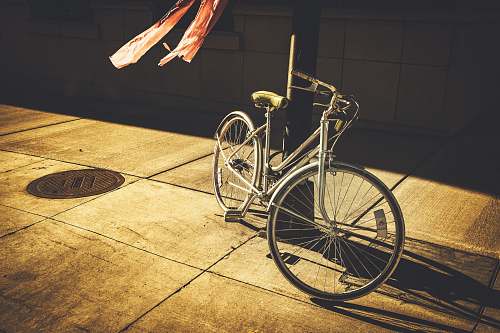 bicycle gray step-through bike leaning on black post bike