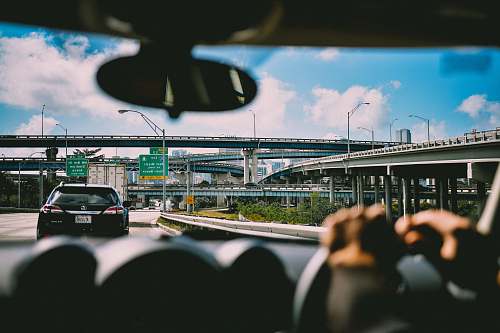 car person sitting on vehicle near car and bridge at daytime freeway