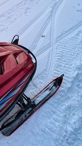vehicle red and black snow sled on snow covered ground during daytime boat