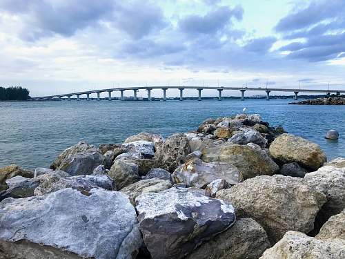 waterfront gray rocks near body of water under cloudy sky during daytime dock