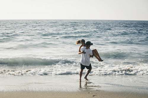 people man carrying woman on seashore beach