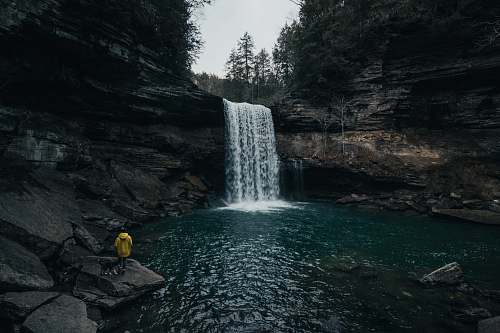 grey person in front of waterfalls waterfall