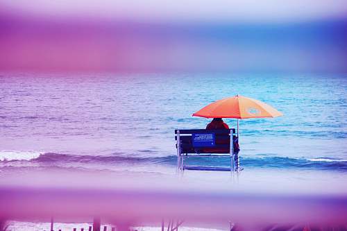 ocean person sitting on lifeguard tower near shore sea