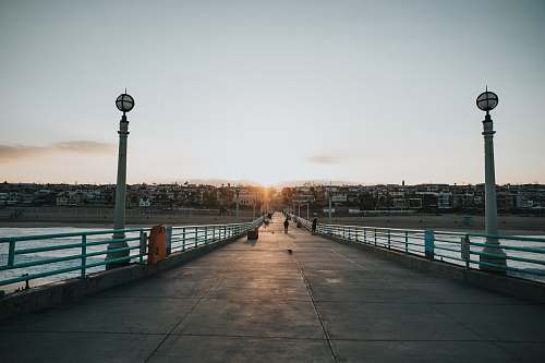 path photography of person walking on bridge during daytime pier