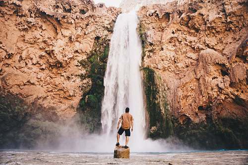outdoors man standing on stone in front of waterfall havasupai reservation