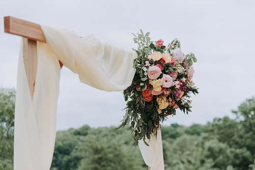 flower bouquet of assorted-color flowers hanged on brown plank with white textile flora