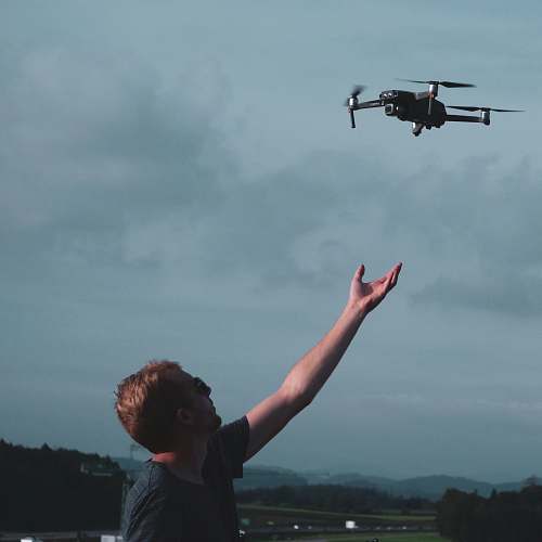 flying man wearing black t-shirt under black quadcopter bird
