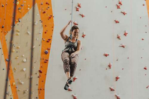 climbing woman holding gray harness near multicolored wal sport