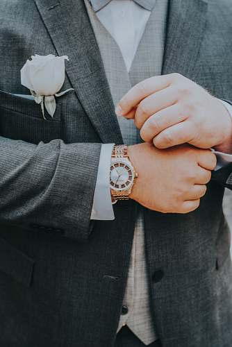 clothing person wearing grey tuxedo and gold-colored watch with white rose brooch wristwatch