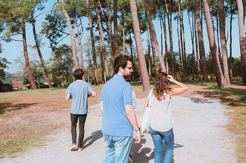 clothing two men and woman walking towards trees denim