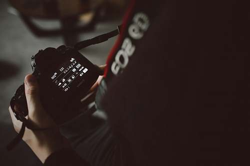 canon person holding black DSLR camera photographer