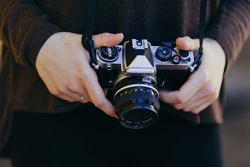human person holding gray and black SSLR camera person