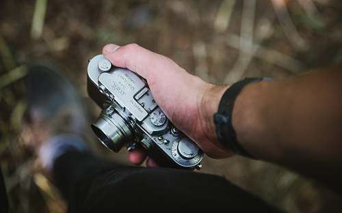 photography person holding silver point-and-shoot camera vintage