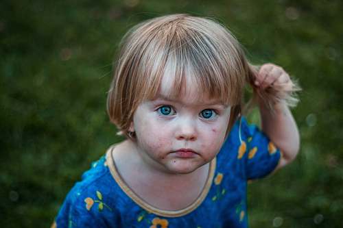 childhood selective focus photography of girl holding her hair toddler