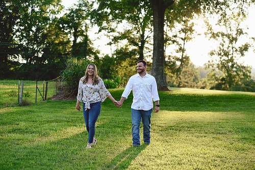 apparel couple walking at grass lawn away from tree pants
